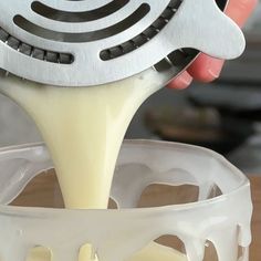 a person pouring milk into a bowl with a whisk on it's side