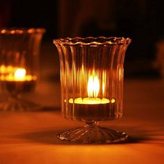 two lit candles sitting on top of a table