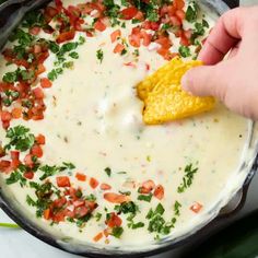 a hand dipping a tortilla chip into a pot of quesadilla