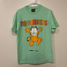 Garfield The Hundreds T-Shirt Size S Style: Short Sleeve T-Shirt Color: Mint Green And Yellow, Multicolor Size: S New With Tags! Nwt Green Casual T-shirt With Cartoon Print, Yellow Crew Neck T-shirt With Cartoon Print, 90s Style Yellow Cotton T-shirt, 90s Style Green T-shirt For Spring, Green Logo Print Shirt For Summer, Green Retro Tops With Logo Print, Retro Green Tops With Logo Print, Retro Green Top With Logo Print, Green Logo Print Summer Shirt