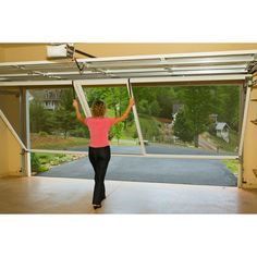 a woman is standing in front of an open garage door and stretching her arms to the side