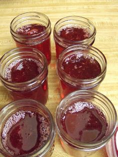 several jars filled with jam sitting on top of a wooden table