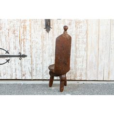 an old wooden chair sitting in front of a white wall with a hook on it