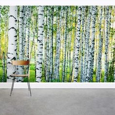 a chair sitting in front of a wall mural with trees painted on the walls and grass behind it