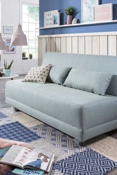 a blue couch sitting on top of a rug in a living room next to a lamp