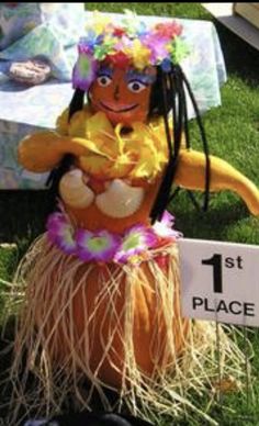 a fake hawaiian hula dancer sitting in the grass next to a sign that says 1st place