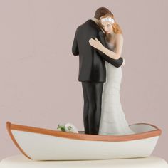 a wedding cake topper with a bride and groom in a boat