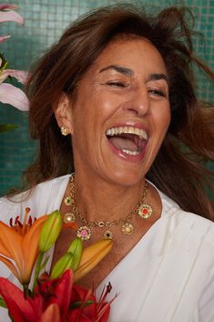 a woman laughing and holding a bouquet of flowers in front of her face while wearing a white shirt