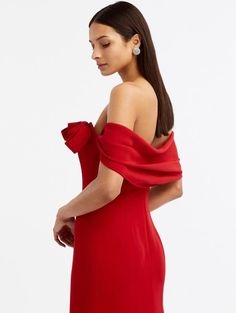 a woman in a red dress is looking down at her left shoulder and she has one hand on her hip