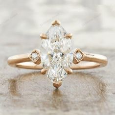 an engagement ring with a pear shaped diamond in the center and three diamonds on each side