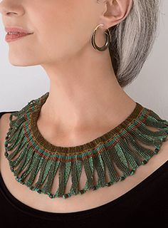 a woman with grey hair wearing a green necklace and matching earring set on her neck