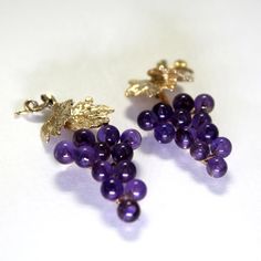 "This lovely set of natural looking grape cluster earrings feature two overlapping 14kt. yellow gold pinot noir grape leaves with a lot of fine detail . This design contains twenty four 3mm. Amethyst deep purple gemstones. The Amethyst gemstones are clustered in a natural looking way like an actual cluster of grapes. The earrings have 14kt. Gold posts and backs Actual Size is 1\" tall by 1/2\" wide. I was inspired in the creation of this jewelry by looking at how a actual cluster of grapes are a Elegant Grape Colored Jewelry For Gift, Gem Nail Designs, Purple Gemstones, Grape Earrings, Twenty Four, Birthstone Gifts, February Birthstone, Amethyst Earrings, Cluster Earrings