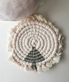 a white and gray woven object sitting on top of a table next to a pillow