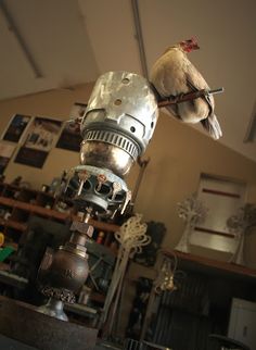 a bird sitting on top of a metal object in a room with lots of furniture