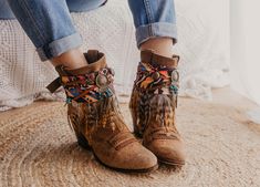 Step into the essence of Western charm with our handcrafted boot covers. Featuring a handmade suede braid and strip adorned with ancient Indian coins and natural khaki hair appliqué, topped with a central dream catcher in old gold. Embrace the spirit of the frontier with these unique and stylish boot accessories, perfect for adding a touch of rustic elegance to any ensemble. SPECIFICATIONS * Tribal boot covers * Made with multicolor ethnic printed scarf base and strip of feathers in beige tones Bohemian Winter Suede Boots, Bohemian Suede Winter Boots, Bohemian Brown Suede Boots, Leather Bohemian Boots For Festival, Bohemian Multicolor Boots For Festivals, Multicolor Bohemian Boots For Festivals, Bohemian Moto Boots With Round Toe For Fall, Bohemian Moto Boots For Festival In Fall, Multicolor Western Festival Boots