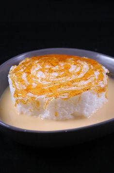 a piece of cake on a plate with cream and orange sauce in the bowl next to it