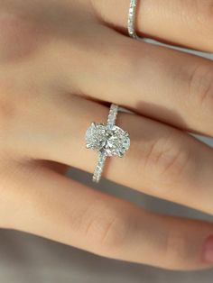 a woman's hand with an engagement ring on it and two diamond rings in the middle