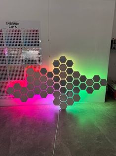 a room that has some lights on the floor and a wall with hexagonal shapes