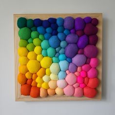 a wooden frame with multi colored felt balls on it and a white wall in the background