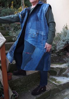 an older man is standing on some steps wearing a blue jean vest and black shoes