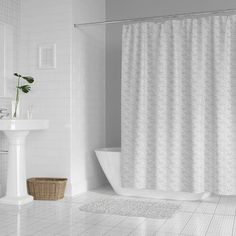 a white bathroom with a tub, sink and shower curtain