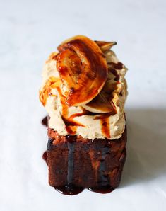 a piece of cake with bananas and ice cream on top is sitting on a white surface