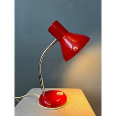 a red desk lamp sitting on top of a table