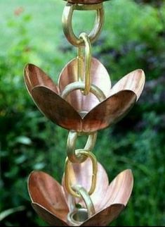 a wind chime hanging from the side of a tree in front of some bushes