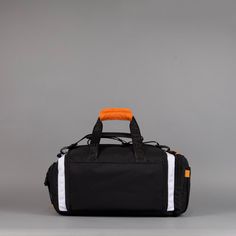 an orange and white duffel bag on grey background