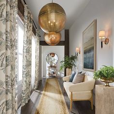 a long hallway with two chairs and a rug on the floor in front of windows