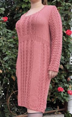 a woman standing in front of a rose bush wearing a pink sweater dress and thigh high socks