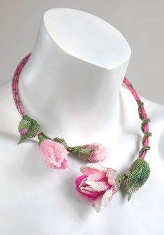 a white mannequin with pink flowers and green leaves on it's neck