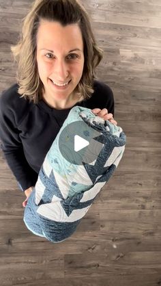 a woman holding up a blue and white quilt