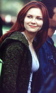 a woman with red hair is smiling at the camera