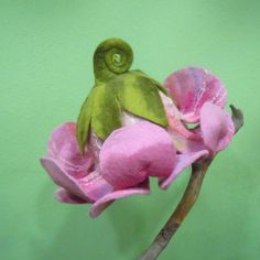 a stuffed animal sitting on top of a pink flower next to a green wall in a room