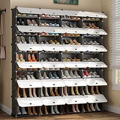 the shoe rack is filled with many pairs of shoes and has multiple bins on each side