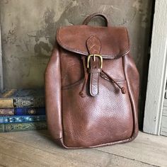 "Vintage Chestnut Brown Leather Backpack 1980s by Robert Cheau Leather drawstring top, one front pocket with strap & buckle closure, roomy interior with one interior zipper pocket, solid brass hardware. Marked Robert Cheau under front flap, made in USA. High quality made. Thick & wide adjustable leather straps. Beautiful full grain leather. Great color and patina. Excellent quality handcrafted. Measures; 12.5\" height, 9.5\" length, approx. 4\" depth, this is a fairly heavy bag, as the l Vintage Brown Leather Backpack For Everyday, Brown Vintage Leather Backpack, Classic Everyday Backpack With Hasp Closure, Retro Brown Leather Backpack, Vintage Standard Backpack For Everyday, Vintage Style Everyday Backpack, Vintage Backpack With Leather Backing, Vintage Brown Leather Satchel Backpack, Vintage Leather Satchel Backpack For Everyday