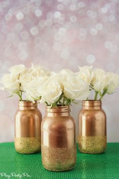 three vases filled with white flowers on top of a green table