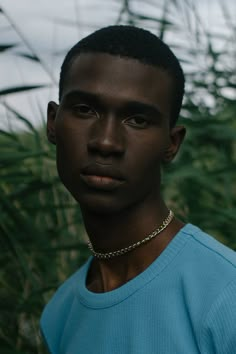 a young man wearing a chain around his neck and looking at the camera with an intense look on his face