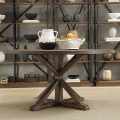 a wooden table sitting in front of a book shelf filled with vases and bowls