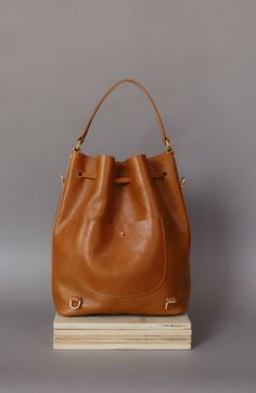 "Perfect leather bucket bag for any occasion, it will be ideally for traveling, because at any moment you can put it on as a backpack. This color of the handbag will make you stand out from the crowd Leather women's bag type sack / backpack 3in1 is the latest proposal from Kulikstyle. Leather bucket bag is not only very \"smart\" but also stylish. A cool every day or night bag, made of 100% italian PREMIUM leather in CAMEL color. A comfortable and soft shoulder bag for women with drawstring clos Backpack Diy, Accessories 2020, Handmade Leather Purse, Leather Hip Bag, Small Leather Bag, Purse For Women, Brown Leather Bag