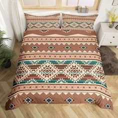 a bed covered in a brown and green comforter next to a plant on a wooden floor