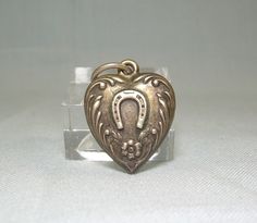 ** We do not clean our items - this has a very dark patina & would polish up brighter silver ** Puffy hollow antique heart in excellent condition, no dents, no damage. The front has a lucky horseshoe & little forget me not flowers, while the back is plain. Very rare to find one with no monogram !  Just about 7/8" (2.2 cm) long overall including the attached bail. Not including the attached bail, it's just about 11/16" (1.75 cm) tall by about 9/16" (1.4 cm) wide by about 3/16" (5 mm) thick. Marke Forget Me Not Flowers, For My Love, Undying Love, Lucky Horseshoe, Sun City, Puffy Heart, Forget Me Not, Very Rare, My Love