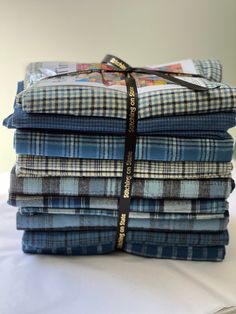 a stack of blue and black plaid fabric on top of a white table cloth with a ribbon