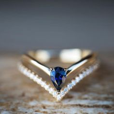 a diamond and blue sapphire ring sitting on top of a rock