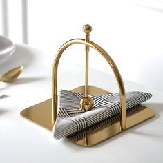 a napkin holder on a white table with gold handles and black and white striped napkins