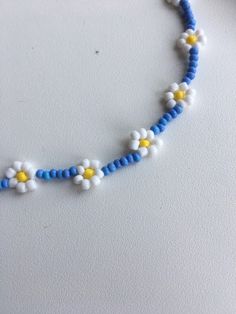 a blue and white beaded necklace with flowers on the end is sitting on a table