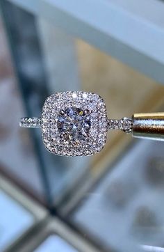 a diamond ring is being held up by a gold stick in front of a glass display case