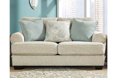 a living room with blue walls and pillows on the back of the couch in front of a window