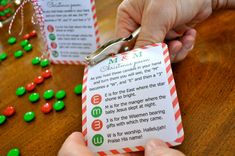 a person is cutting up a christmas letter from a card with scissors and candy on the table